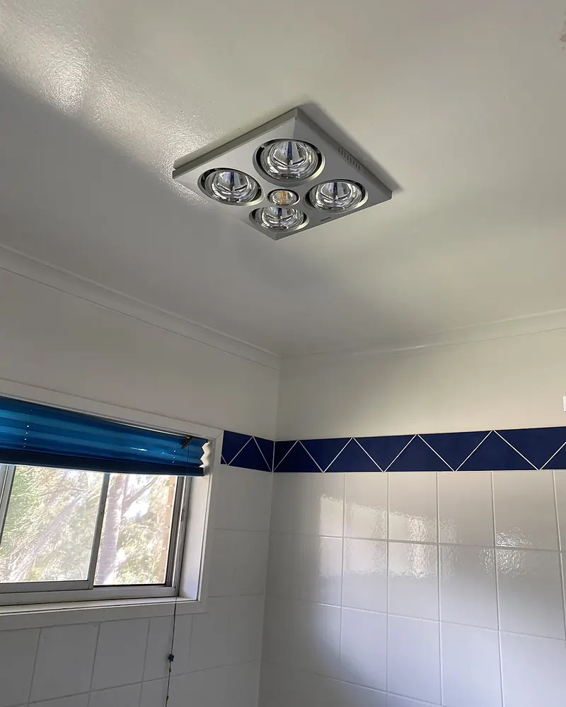 A four lamp bathroom heat and light unit on a white bathroom ceiling