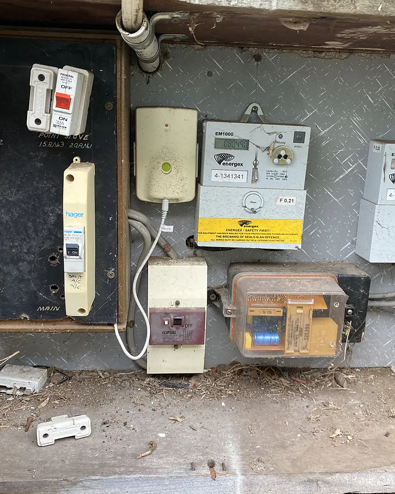 An old fuse board and meters in a timber box, full of dust and debris, before an upgrade