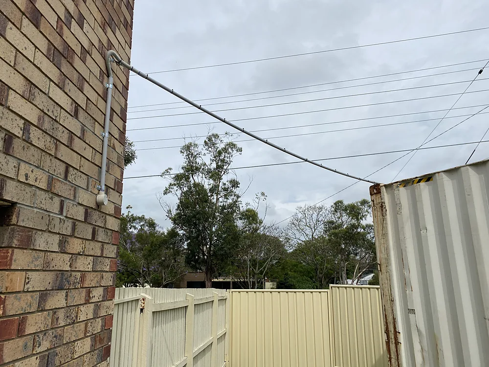 Overhead conduit and cable run from a brick house across the yard to a shipping container shed