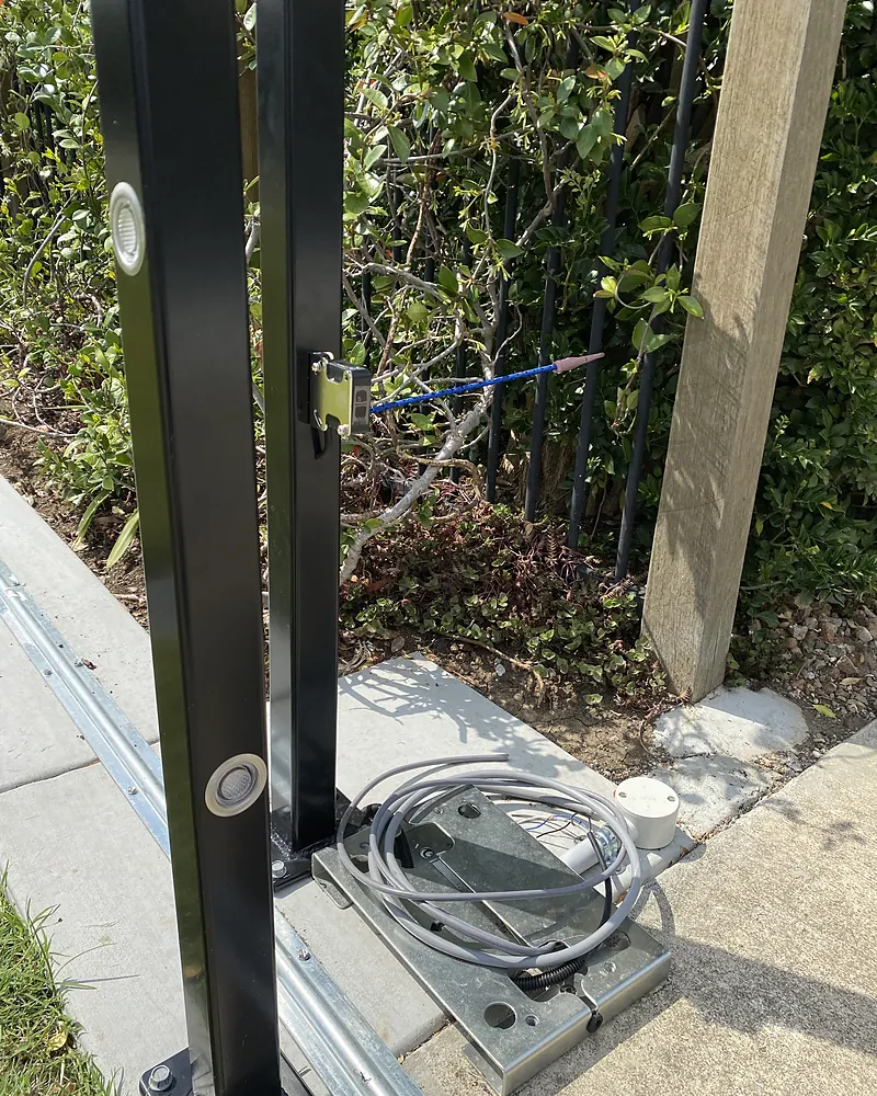 Underground cable brought up to a black gate post beside a footpath